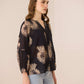 Woman wearing a black blouse with beige floral patterns on a beige background Calling June