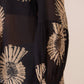 Black blouse with beige floral patterns worn by a person, on a neutral background Calling June