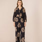 Woman wearing a black floral patterned outfit on a beige background Calling June