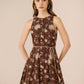 Woman wearing a brown floral dress against a beige background Calling June