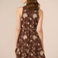 Woman wearing a brown floral dress against a beige background Calling June