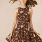 Woman wearing a brown floral dress against a beige background Calling June