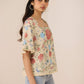 Woman wearing a floral blouse with ruffled sleeves against a beige background Calling June