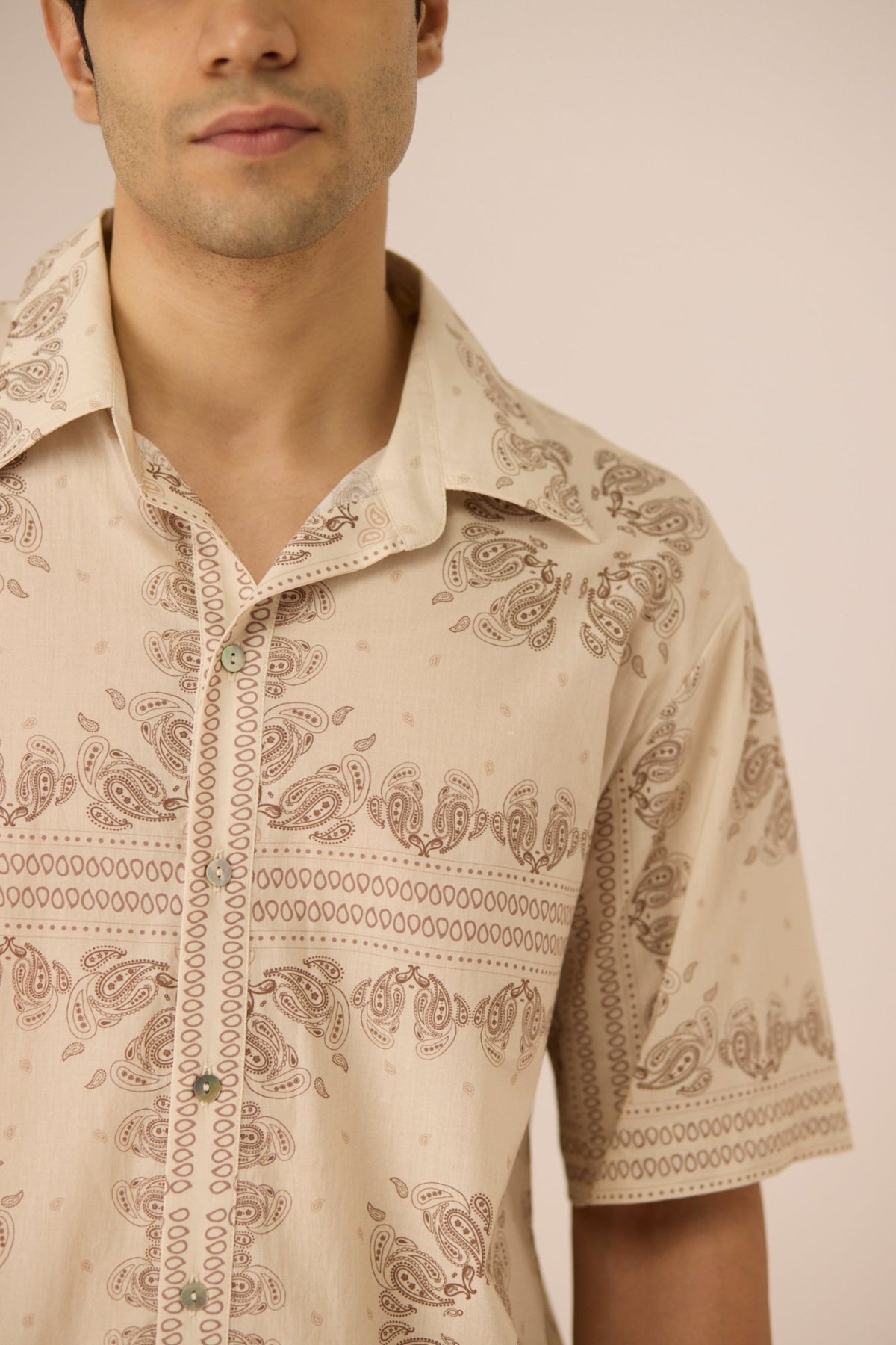 Man wearing a beige patterned shirt against a plain background Calling June
