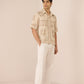 Man wearing a beige patterned shirt and white pants on a beige background Calling June