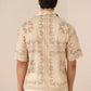 Person wearing a cream embroidered shirt with white pants on a plain background Calling June