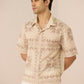 Man wearing a beige patterned shirt against a plain background Calling June
