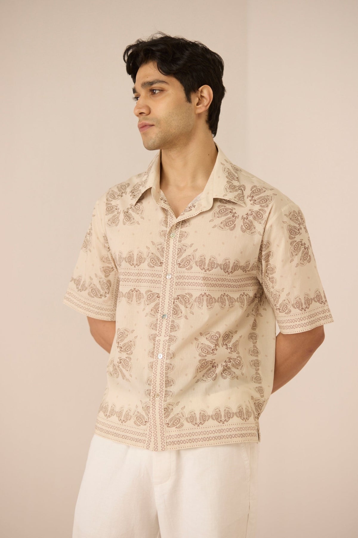 Man wearing a beige patterned shirt against a plain background Calling June