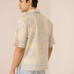 Man wearing a patterned beige shirt and light blue jeans against a plain background Calling June