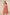 Woman wearing a pink embroidered dress against a beige background Calling June