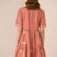 Woman wearing a pink dress with lace details on a beige background Calling June