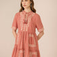 Woman wearing a pink dress with lace details on a beige background Calling June