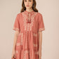 Woman wearing a pink dress with white embroidery on a beige background Calling June