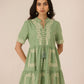 Woman wearing a green embroidered dress against a plain background Calling June