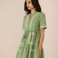 Woman wearing a green dress with floral embroidery against a beige background Calling June