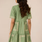 Woman wearing a green dress with embroidery details on a beige background Calling June