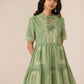 Woman wearing a green dress with embroidery on a beige background Calling June