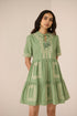 Woman wearing a green dress with embroidery on a beige background Calling June
