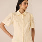 Woman wearing a beige embroidered shirt with short sleeves on a beige background Calling June