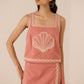 Woman wearing a pink dress with shell design on a beige background Calling June