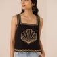Woman wearing a black tank top with gold embroidery against a beige background Calling June