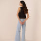 Woman wearing a black sleeveless top with lace details and light blue jeans on a beige background Calling June