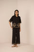 Woman wearing a black outfit with shell patterns on a beige background Calling June
