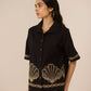 Woman wearing a black outfit with gold embroidery on a beige background Calling June