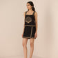 Woman wearing a black dress with gold embroidery on a beige background Calling June
