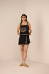 Woman wearing a black dress with gold embroidery against a beige background Calling June