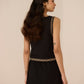 Woman wearing a black dress with gold trim on a beige background Calling June