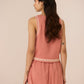 Woman wearing a pink dress with lace trim on a beige background Calling June