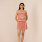 Woman wearing a pink dress with shell design on a beige background Calling June