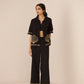 Woman wearing a black outfit with gold embroidery on a beige background Calling June
