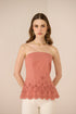 Woman wearing a pink strapless top with floral lace details on a beige background Calling June