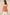 Woman wearing a pink strapless top with floral cut-out details on a beige background Calling June