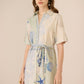 Woman wearing a short-sleeve dress with blue sea-themed patterns on a beige background Calling June