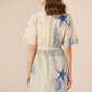 Woman wearing a light-colored dress with blue starfish patterns on a beige background Calling June