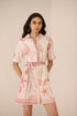 Woman wearing a pink and white dress with shell pattern on a beige background Calling June