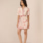 Woman wearing a pink dress with shell pattern on a beige background Calling June