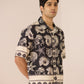 Man wearing a black and white patterned shirt against a plain background Calling June