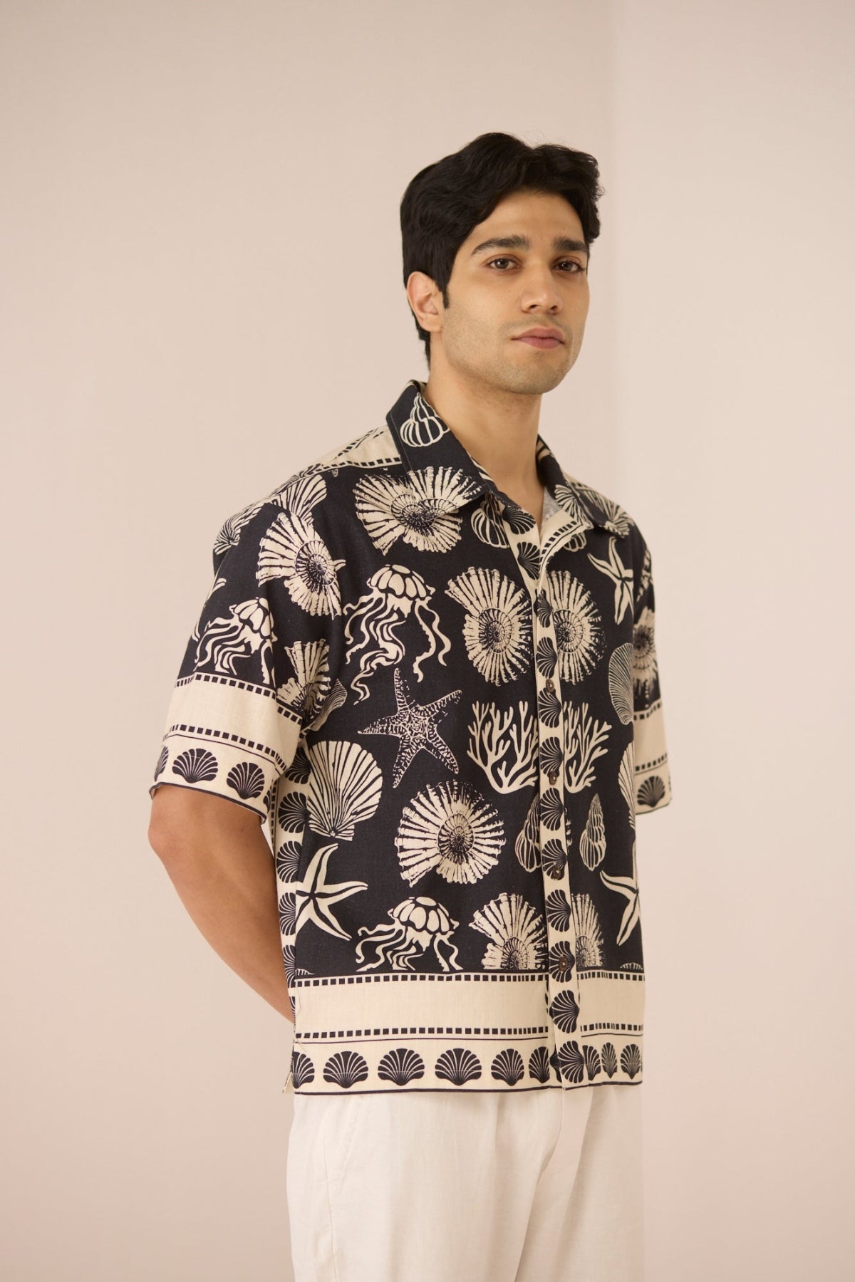 Man wearing a black and white patterned shirt against a plain background Calling June