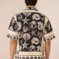 Person wearing a black and white patterned shirt with seashell design on a beige background Calling June