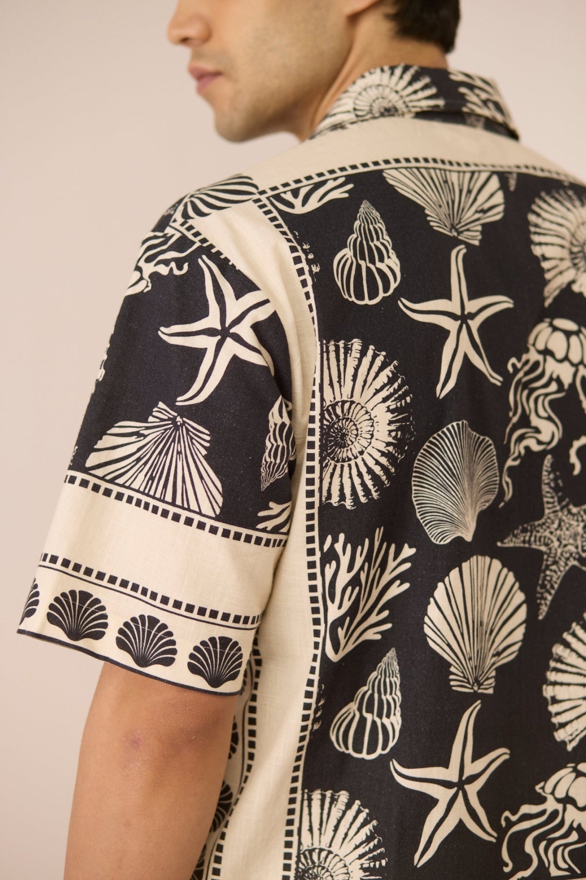 Man wearing a shirt with shell and starfish pattern on a beige background Calling June