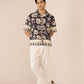 Man wearing a patterned shirt and white pants on a plain background Calling June