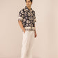 Man wearing a patterned shirt and white pants on a beige background Calling June