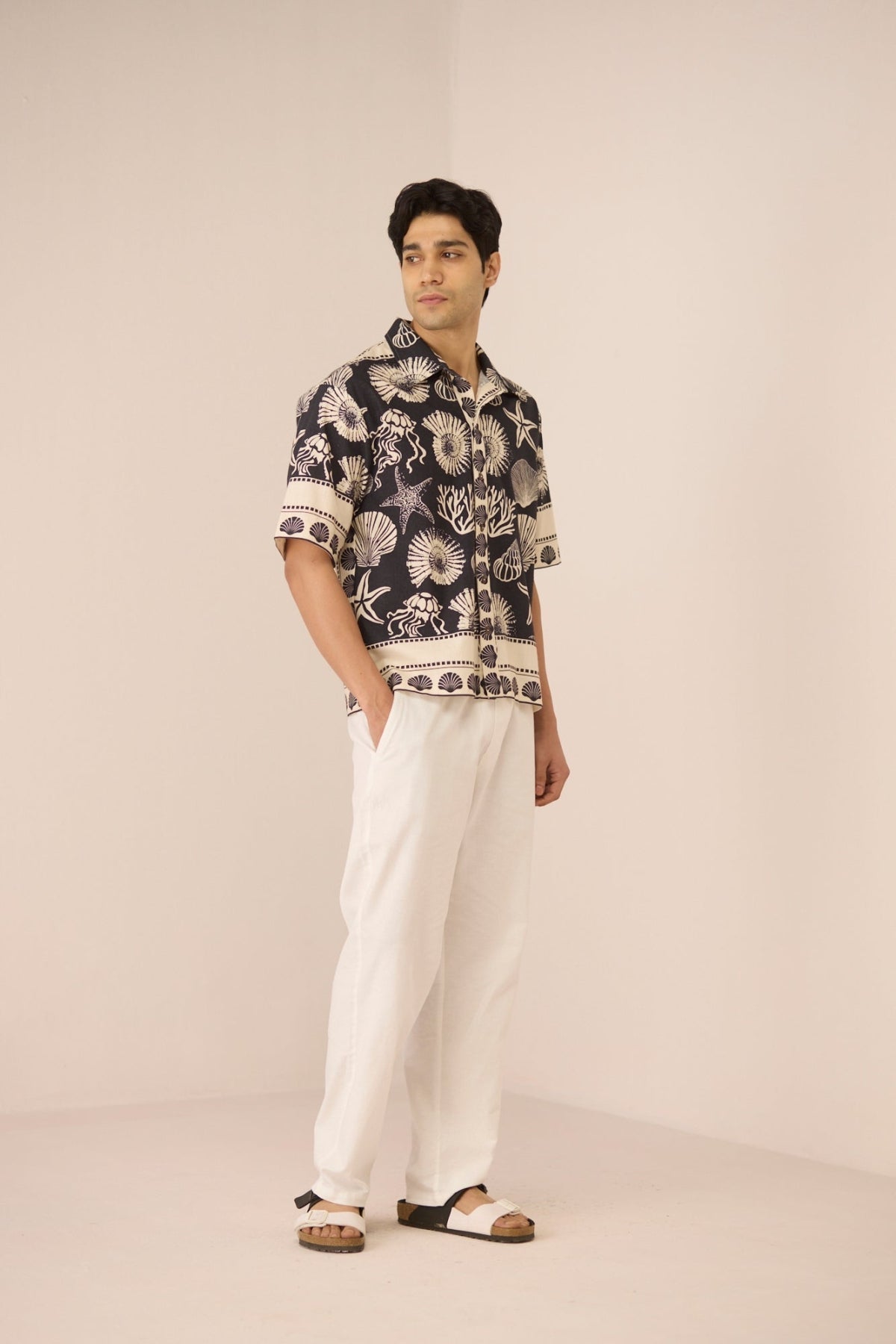 Man wearing a patterned shirt and white pants on a beige background Calling June