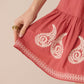 Red dress with white embroidery on a beige background Calling June