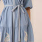 Light blue dress with white embroidery on a beige background Calling June