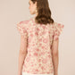 Woman wearing a floral blouse with ruffled sleeves on a beige background Calling June